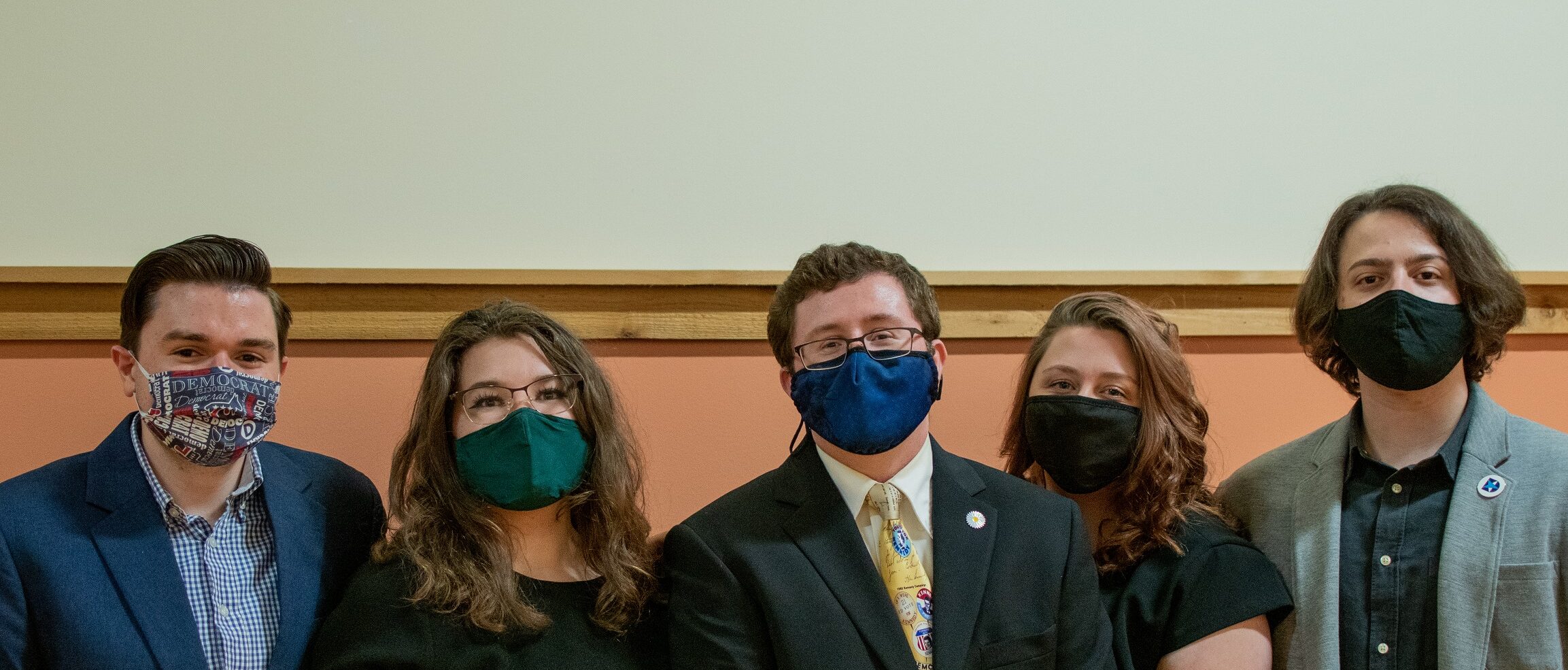 A group of five people in masks standing in a line.
